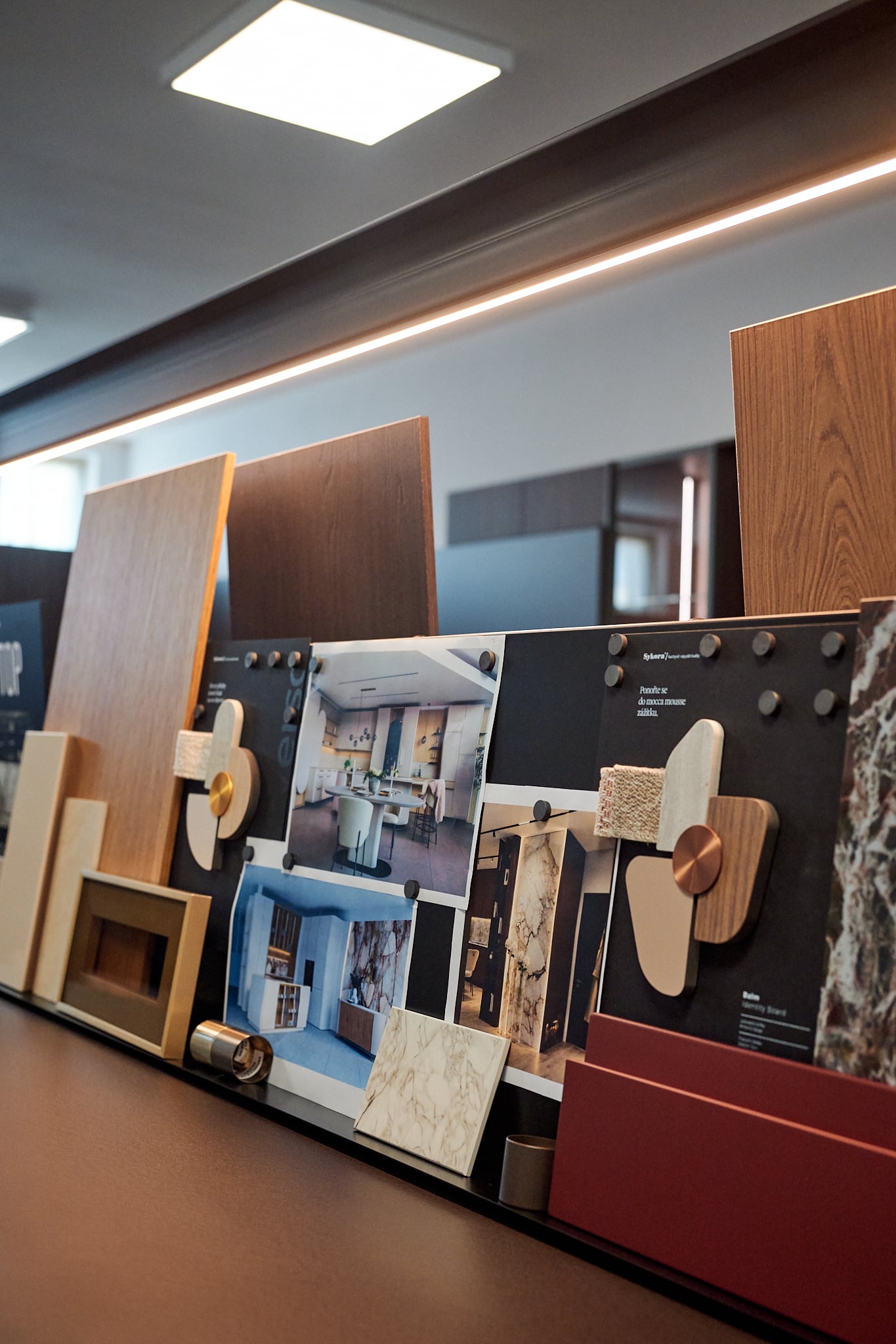 Výstavní desky s materiály a fotografiemi kuchyní v studiu Sykora Trenčín, dřevěné a kamenné vzorky, černá podložka s textem